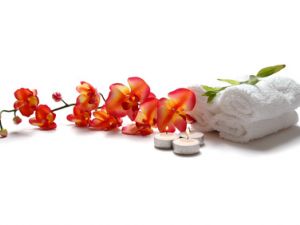 Wellnesshandtücher, Teelichter und eine Orchidee als Teaserbild für das Spezial Ayurveda im Magazin Wohlfühlen
